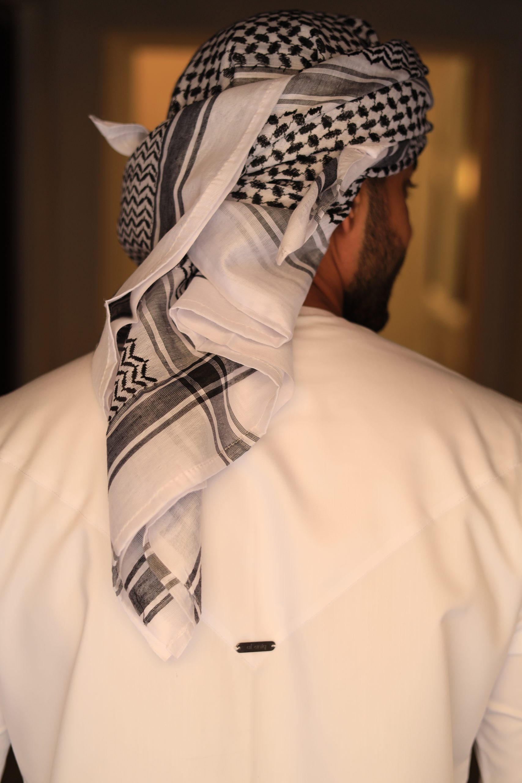 black and white keffiyeh scarf wrapped on the head with a white thobe