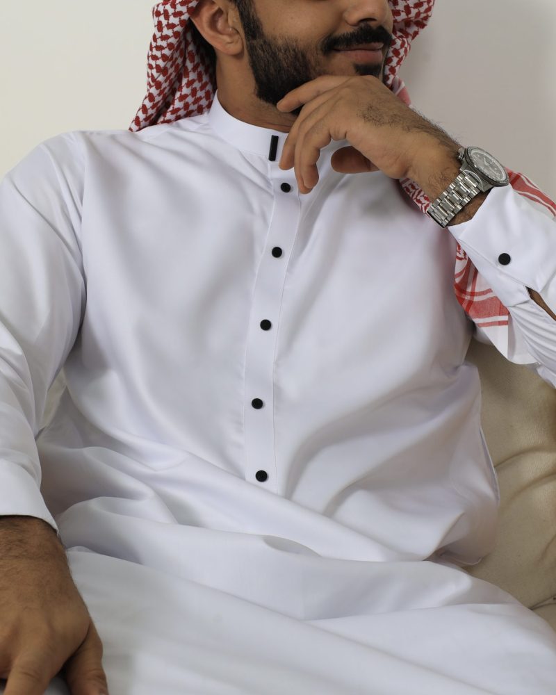 White collar thobe with black buttons styled with a red and white keffiyeh scarf